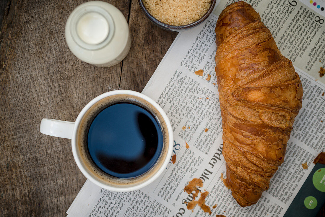 Croissant und Kaffee auf Zeitung