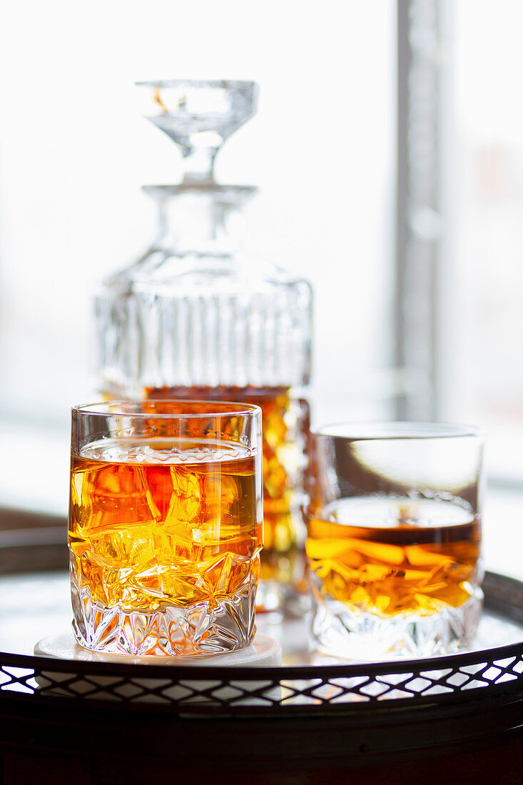 Whiskey in a tumbler alongside a cut glass decanter