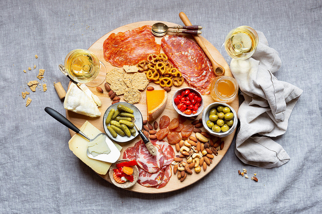 Chacuterie-Platte mit Wurst, Käse, Knabbereien und Weißwein (Aufsicht)