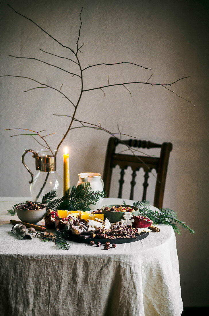Bruchschokolade, Plätzchen und Trockenfrüchte auf winterlich gedecktem Tisch