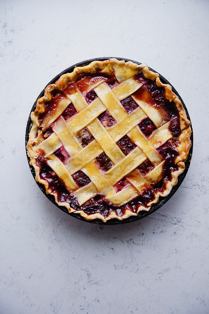 Berry pie with a lattice decoration on concrete background