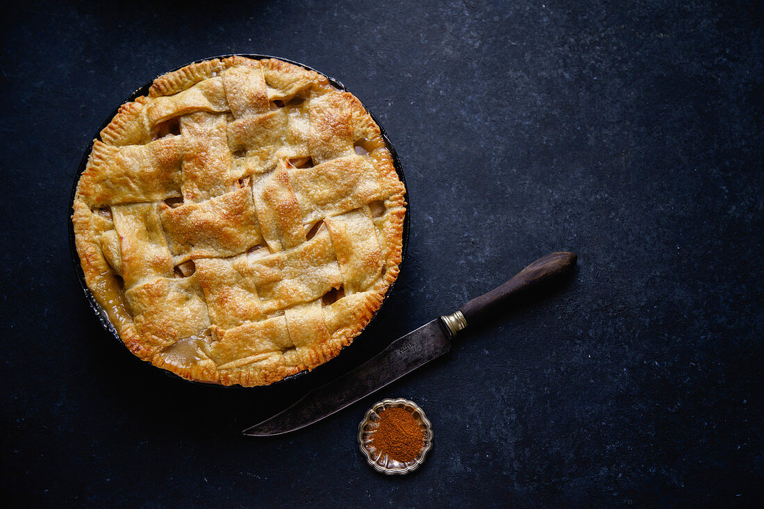 Apple pie with lattice decoration on dark background