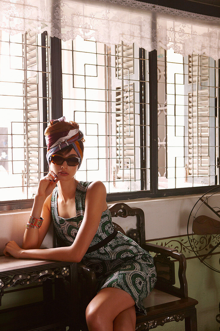 Junge dunkelhaarige Frau im Sommerkleid mit Sonnenbrille und Kopftuch
