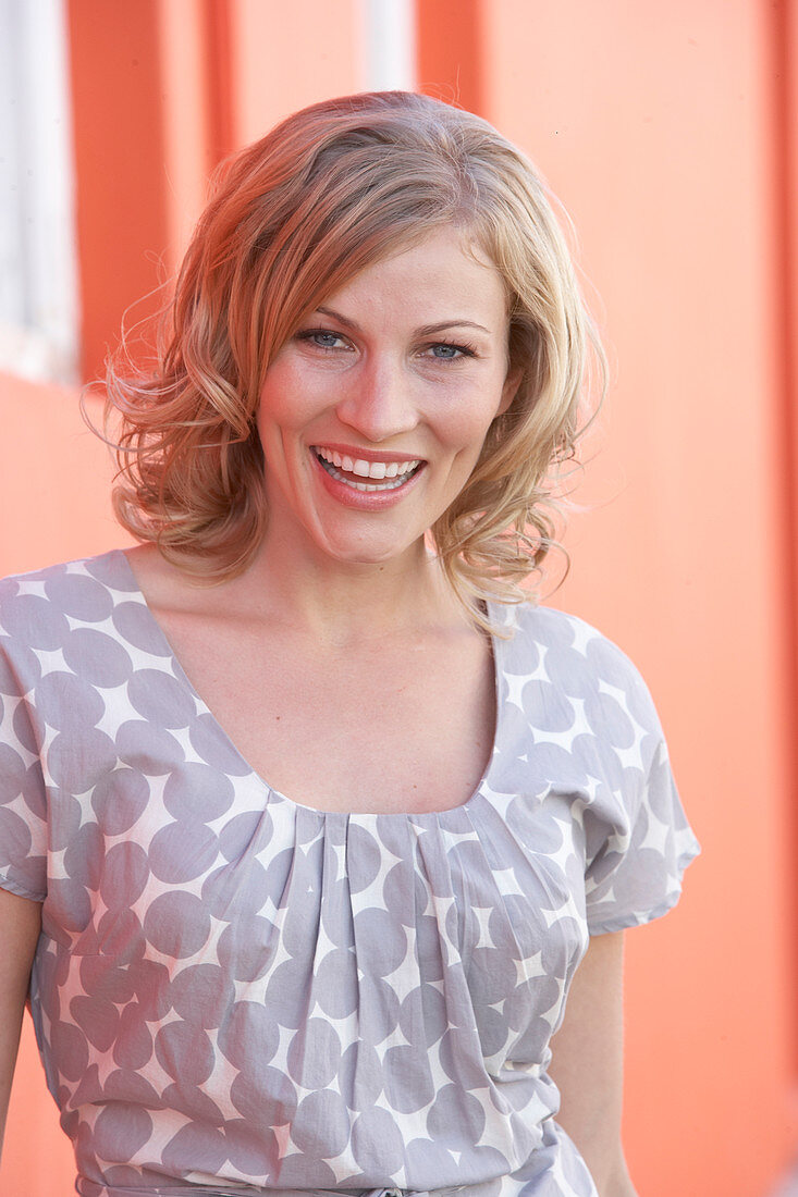 A blonde woman wearing a grey spotted blouse