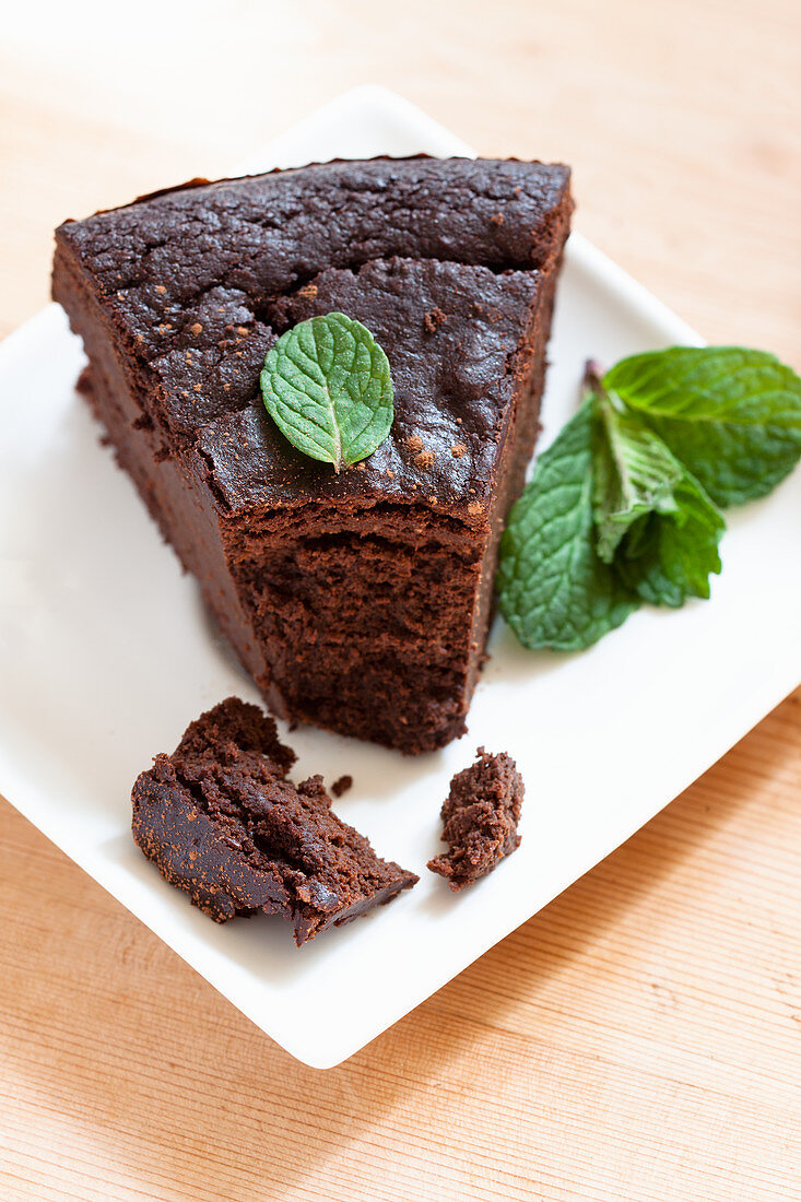 A slice of cocoa and aubergine purée cake with mint leaves
