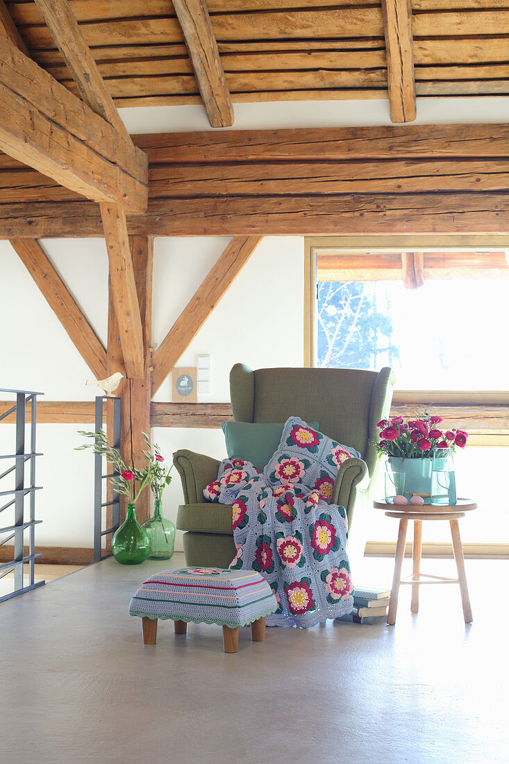 Crocheted blanket and cushion on wingback armchair in country house