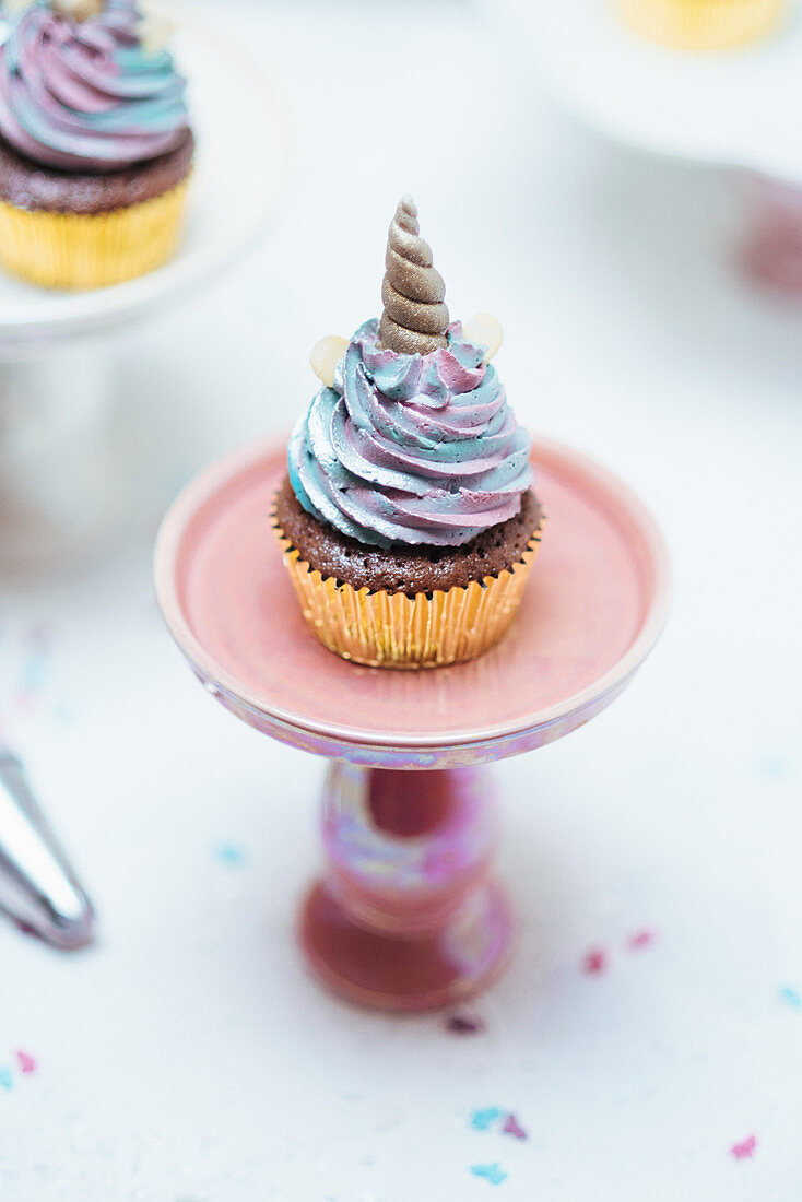 Muffins with pastel coloured frosting decorated with unicorn horns