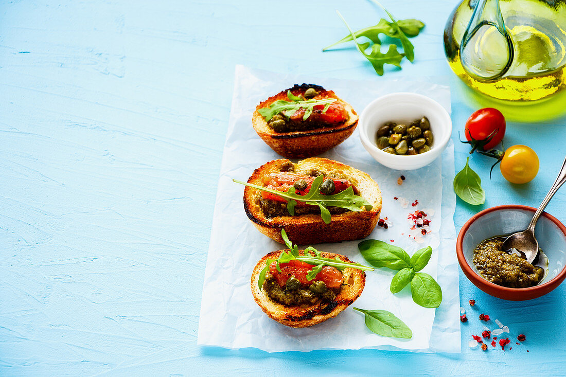 Fresh smoked salmon toasts with arugula, pesto sauce and capers