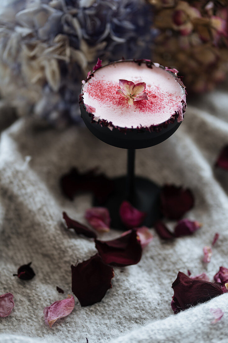 Weisser Wodka-Cocktail mit Himbeerpulver mit Rosenblütenrand