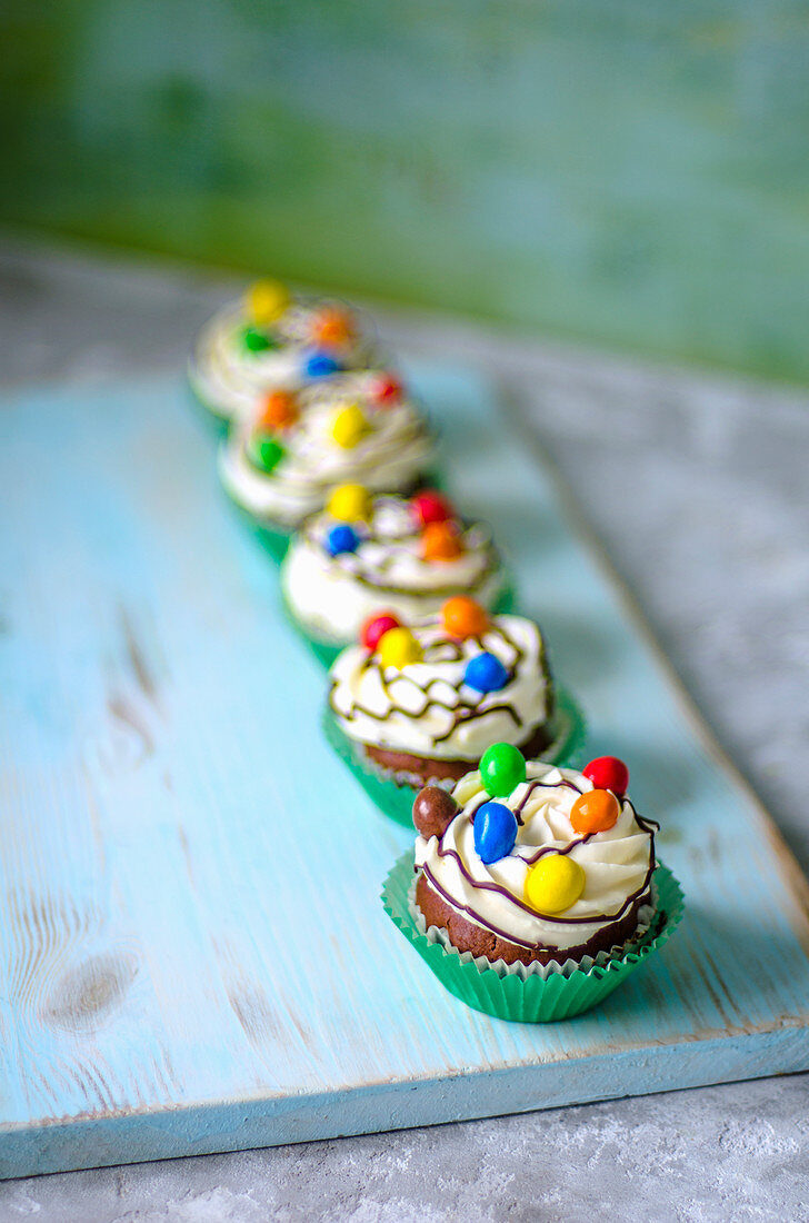 Chocolate cupcakes in green paper forms with butter cream and colored candies