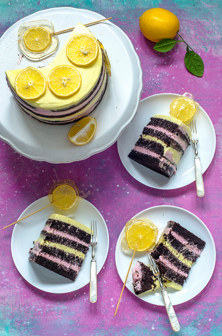 Chocolate naked cake with pink and yellow cream, decorated with candy with slices of lemons