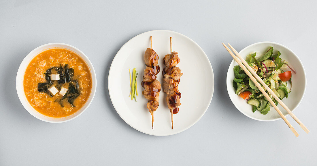Japanese appetizers: miso soup, kebabs and a vegetable salad (seen from above)
