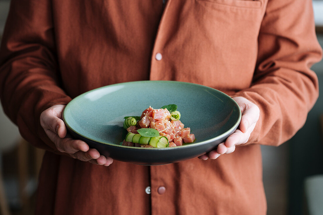 A person holding a bowl of fish tartare