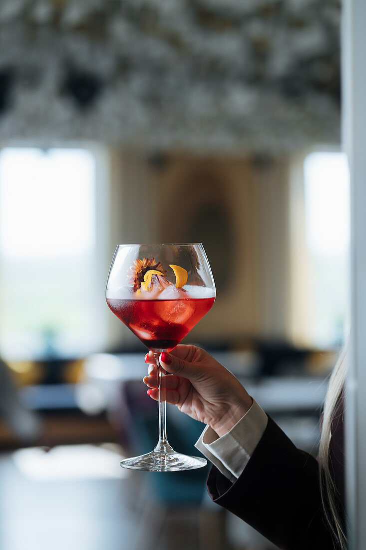 A woman holding a cocktail in a stemmed glass