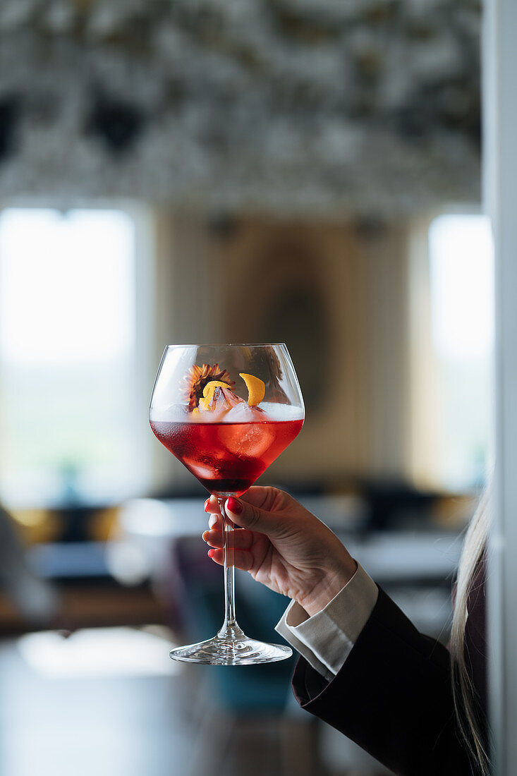 Frau hält Cocktail im Stielglas in der Hand