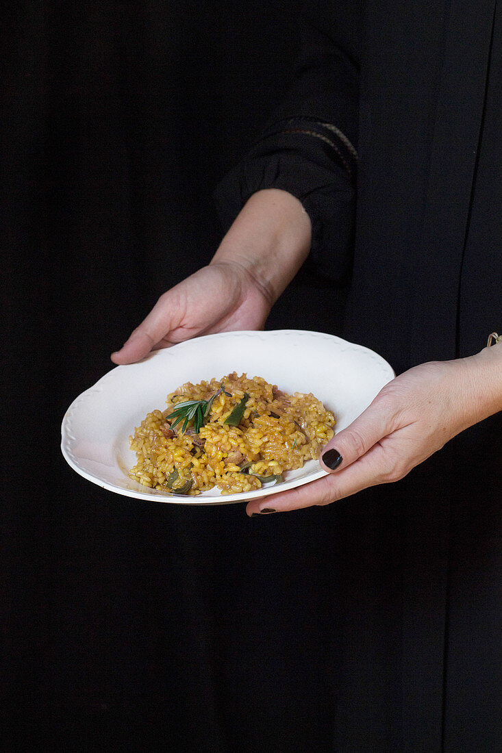 Hands holding plate with risotto