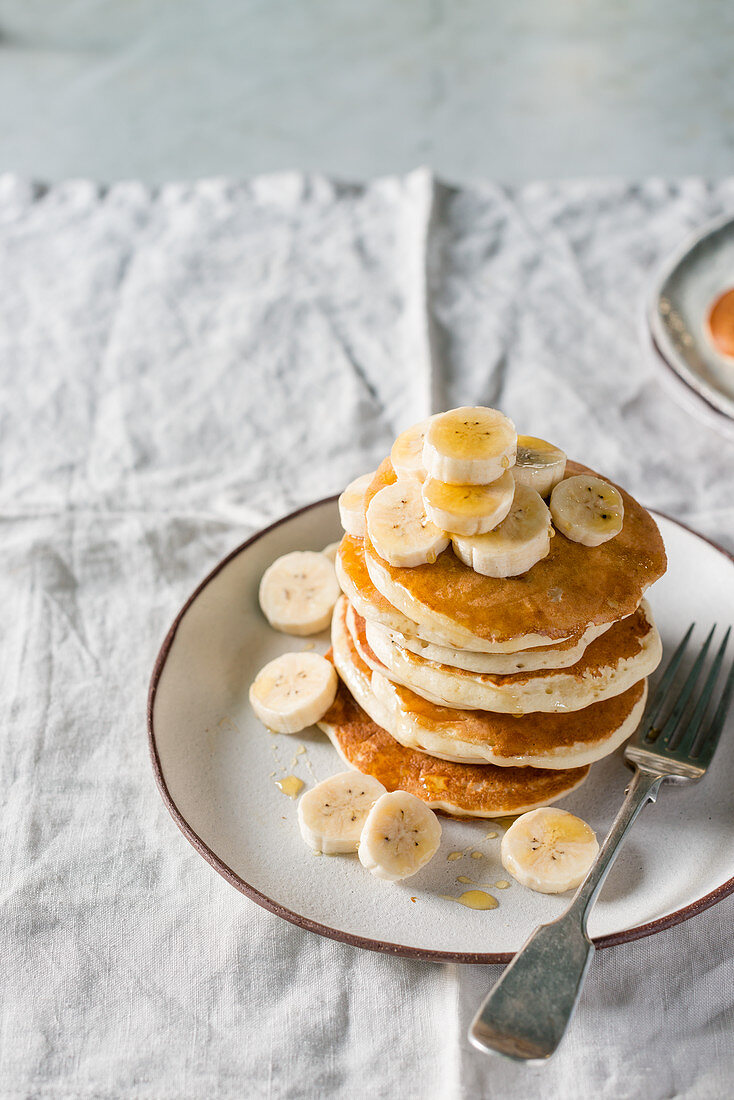 Stack of banana pancakes with fresh banana slices