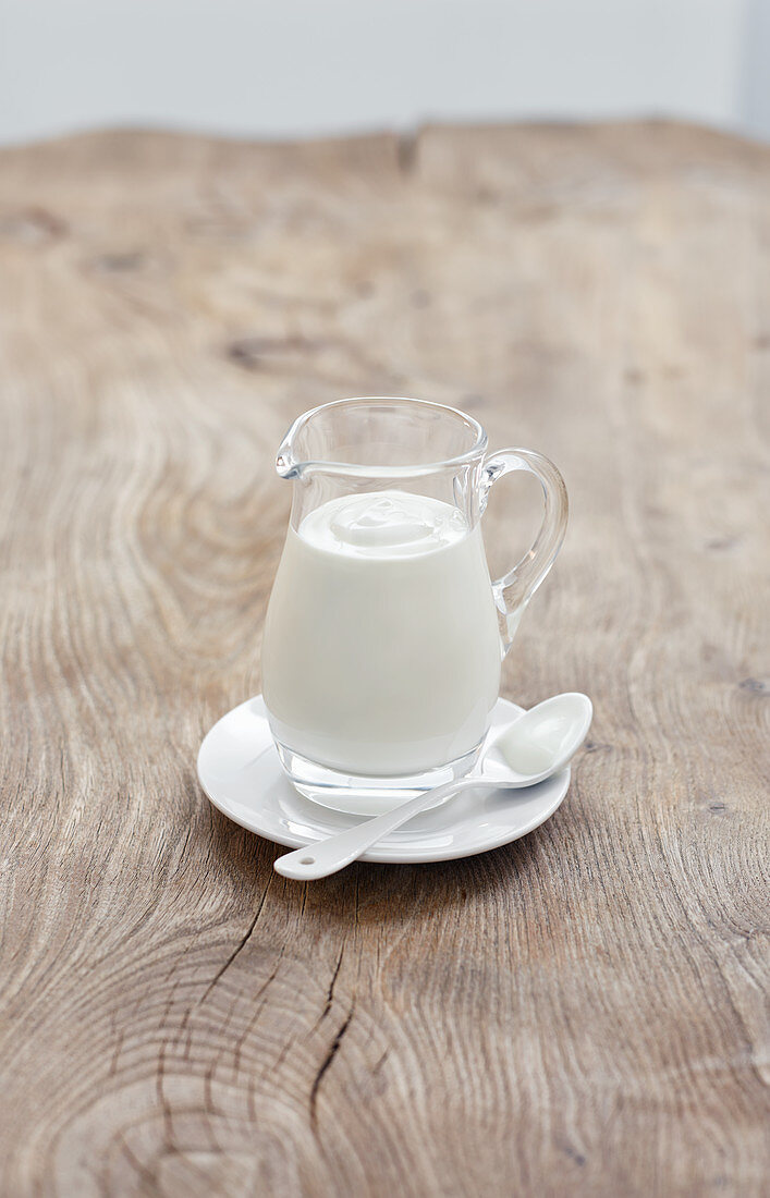 Buttermilch im Glaskännchen auf Holztisch