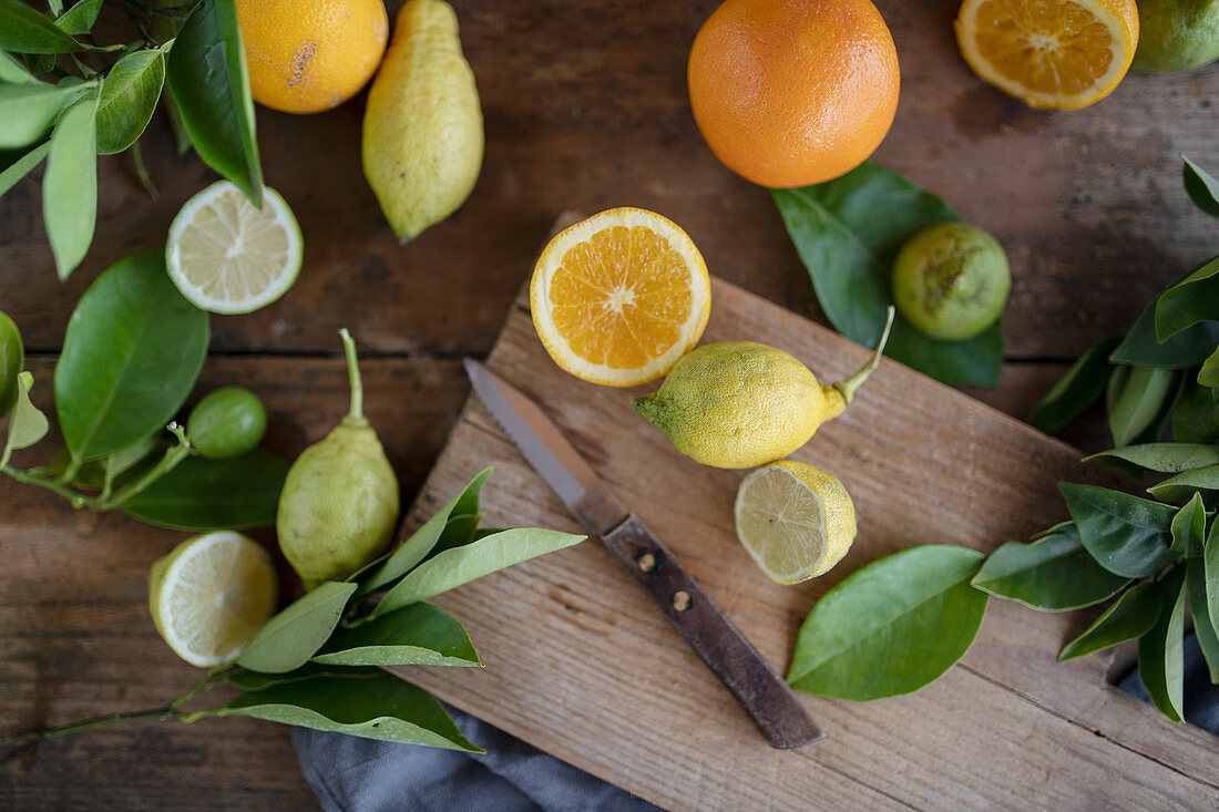 Bio-Orangen und Zitronen mit Messer auf rustikalem Holzbrett