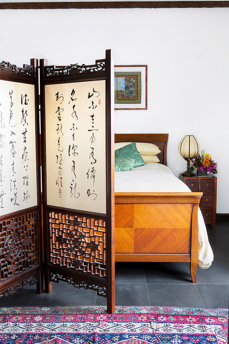 Paravent mit chinesischen Schriftzeichen vor Vintage Doppelbett aus Holz