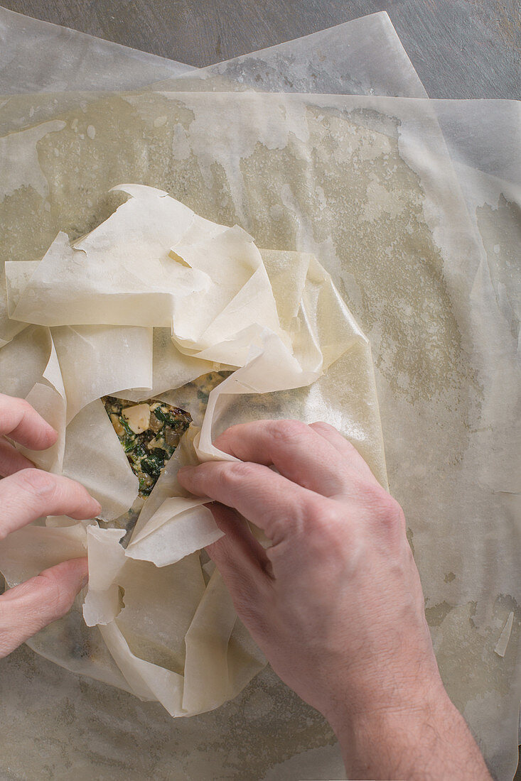 A cook making spanakopita (filo pastry with spinach and feta cheese, Greece)