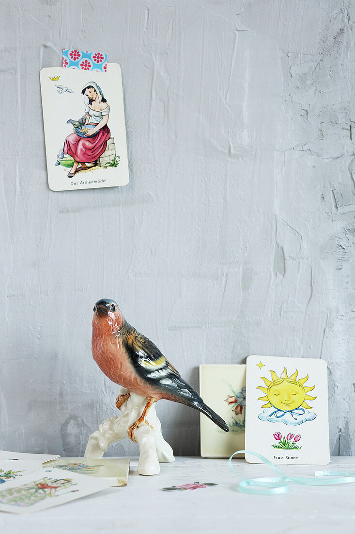 China bird and vintage-style playing cards against grey wall