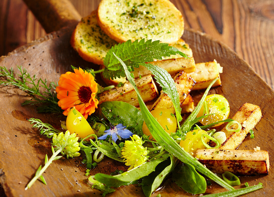 Wild herb salad with roasted tofu, yellow tomatoes and a herb baguette