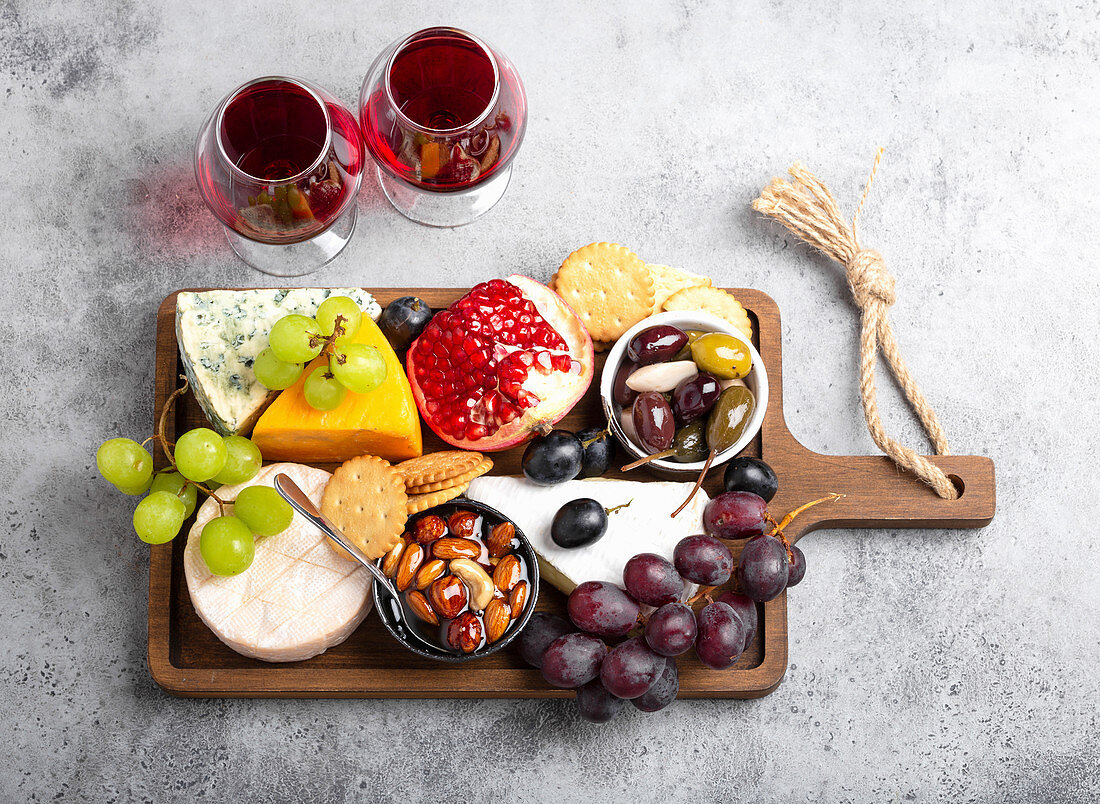 Selection of cheese and appetizers, red wine, camembert, brie, cheddar, cracker, grapes, nuts and honey