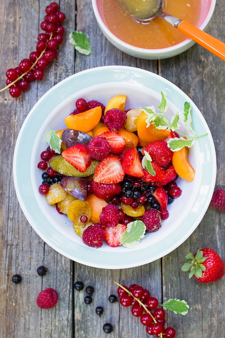 Fruit salad with summer fruits on a wooden table