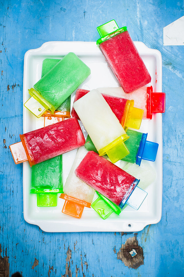 Various homemade popsicles on a blue wooden background