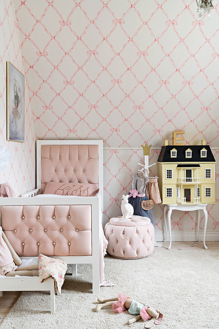 Bed, pouffe and dolls' house in girl's bedroom in pale pastel shades
