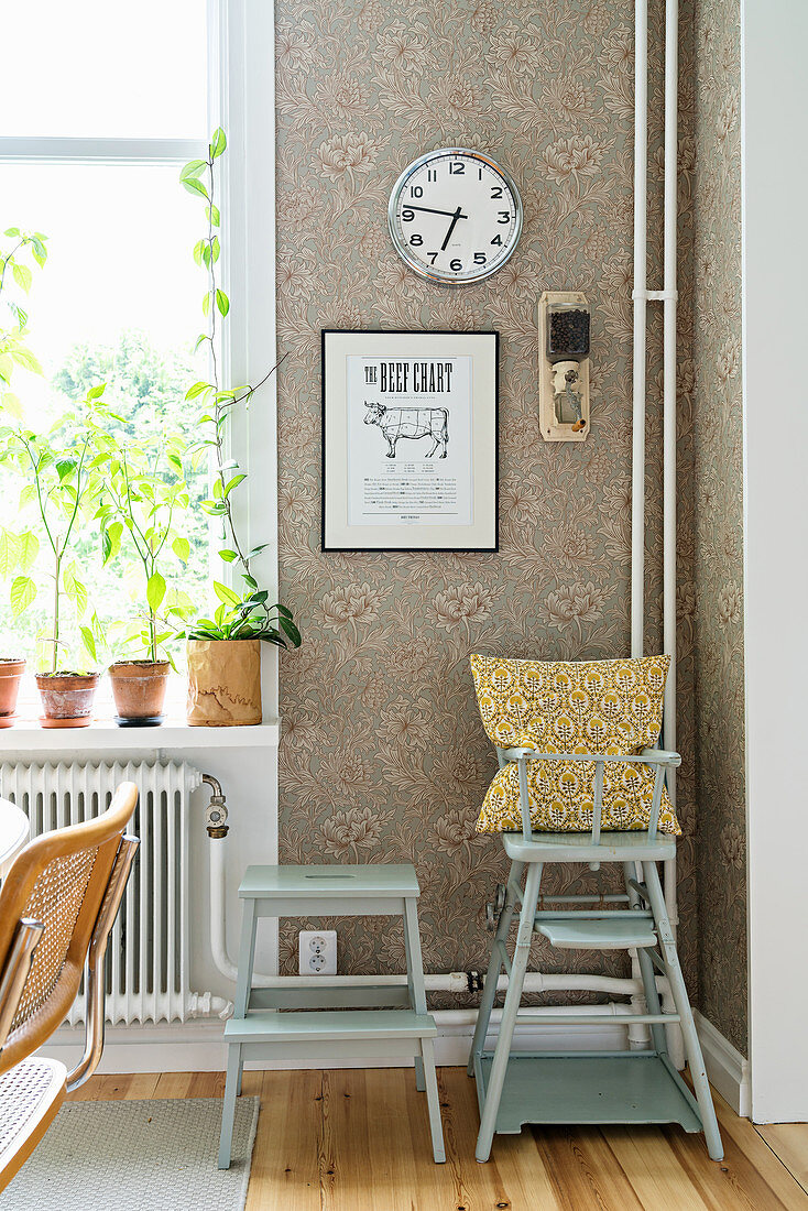 Blue-grey high chair and stool against vintage wallpaper