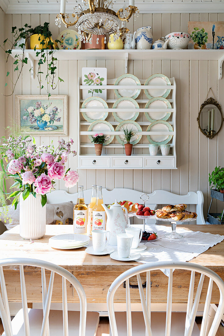 Rustic table in front of plate rack in kitchen-dining room with wood-clad wall