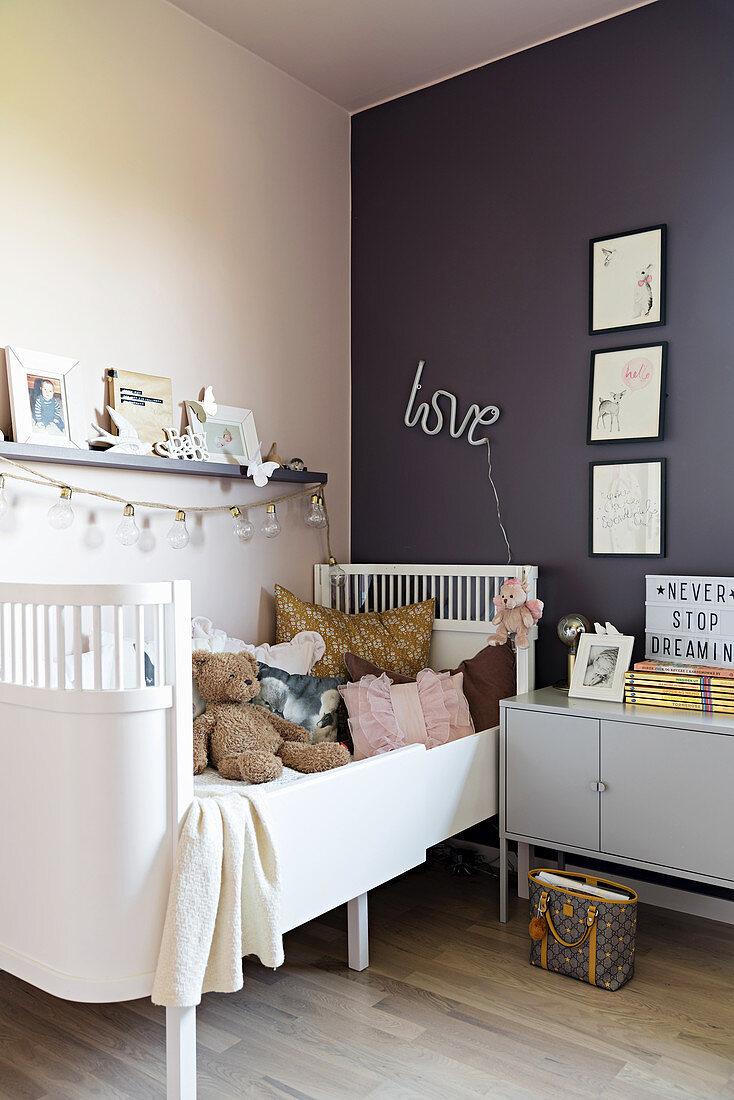 White child's bed and bedside cabinet in girl's bedroom with pink and purple wall