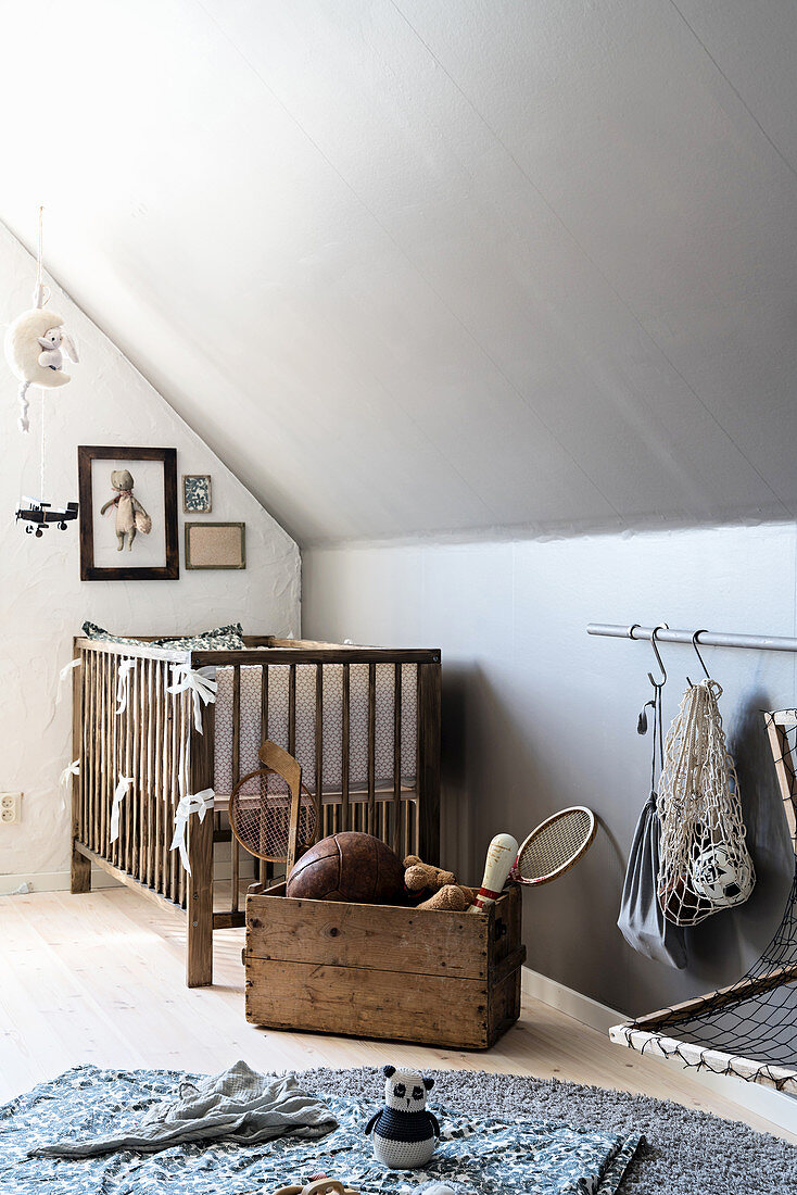 Cot against knee wall in vintage-style nursery