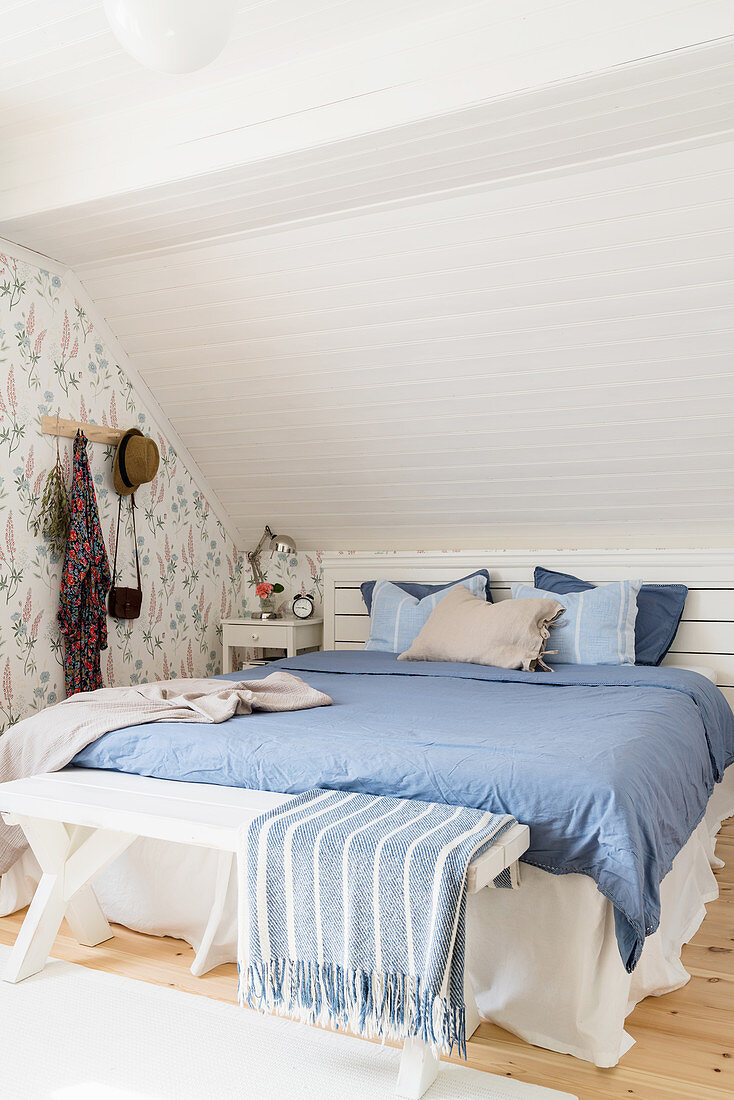 Bed below sloping ceiling in blue-and-white bedroom