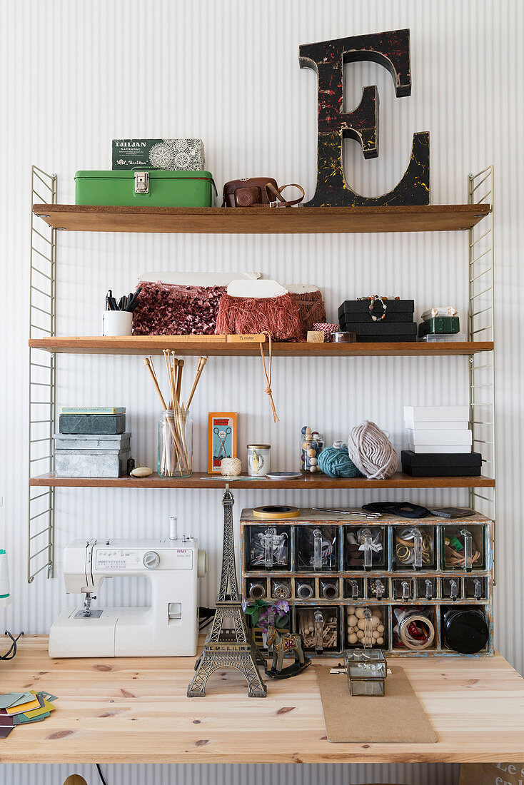 Vintage accessories and decorative letter on shelves above sewing table