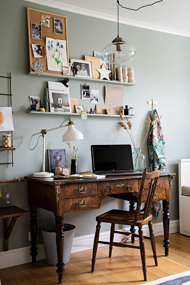 Antique, dark wood desk below shelves on grey wall