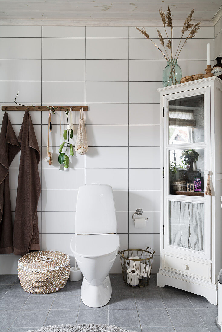 Toilette im Bad mit horizontalen Fliesen und Boho-Deko