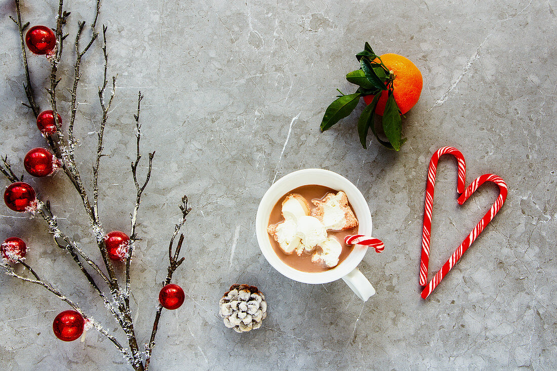 Eine Tasse heiße Schokolade mit Sahne daneben Mandarine und Weihnachtsdekoration