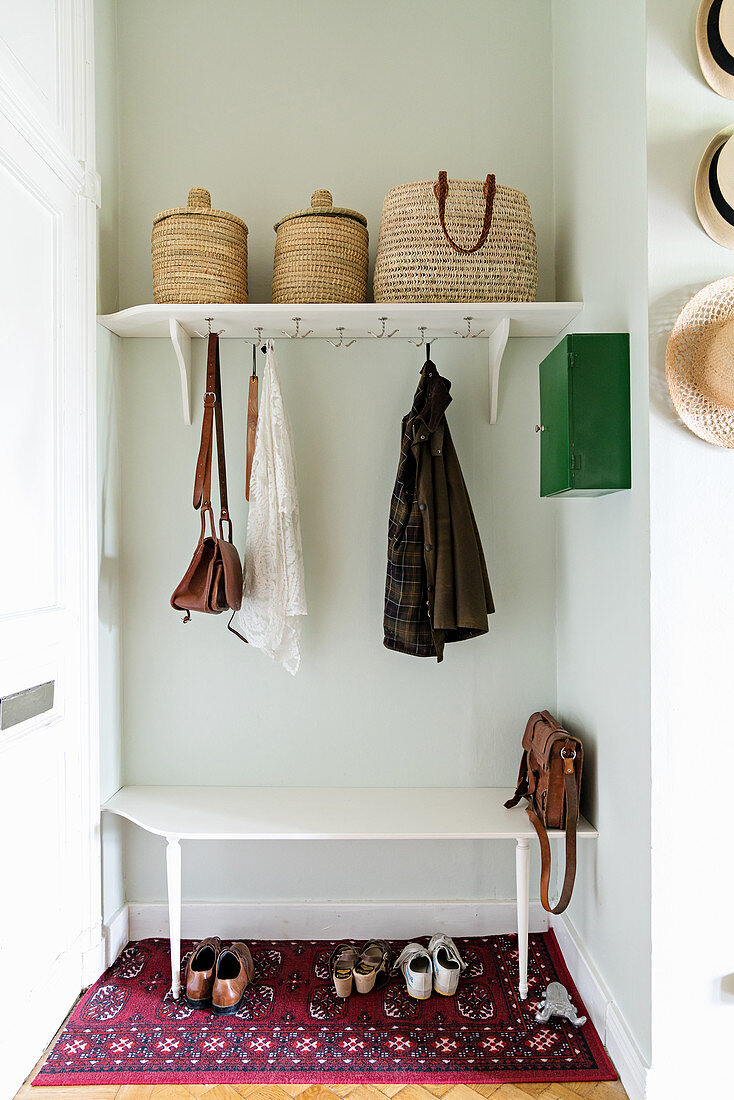 Vintage-style cloakroom in niche with coat pegs below shelf