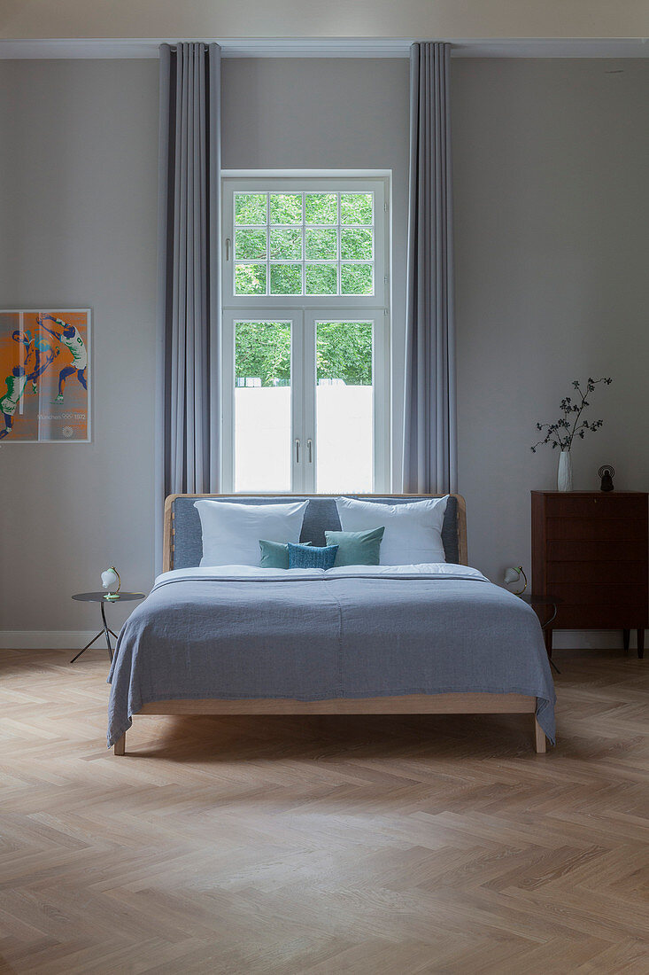 Double bed in front of window in bright, spacious bedroom