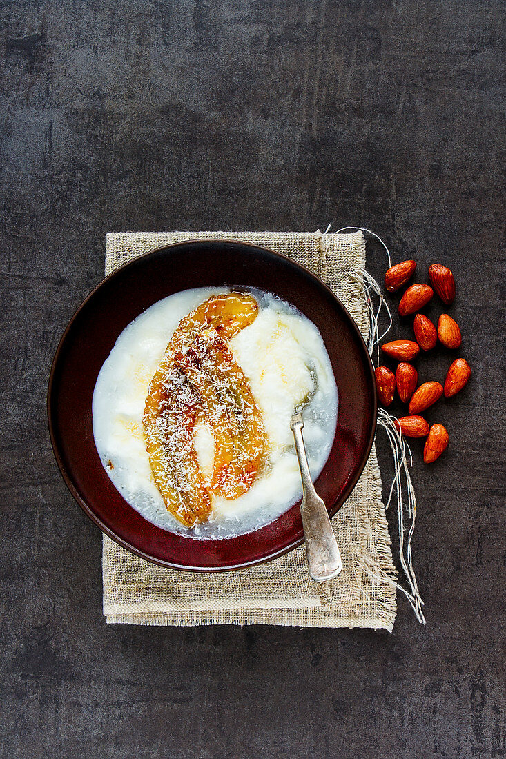 Bowl of greek yogurt with grilled banana, coconut and maple syrup