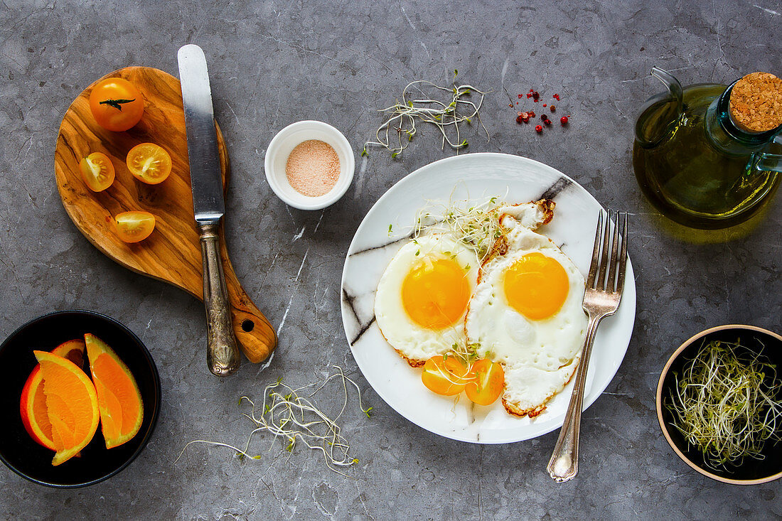 Breakfast with fried eggs, micro greens and tomatoes flat lay