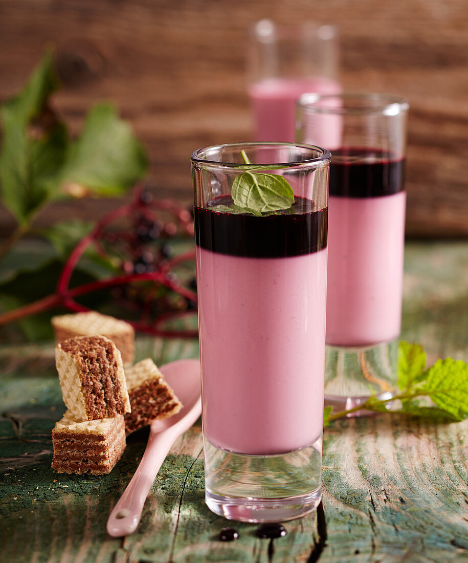 Elderberry panna cotta in glasses with mint, elderflower syrup and wafers