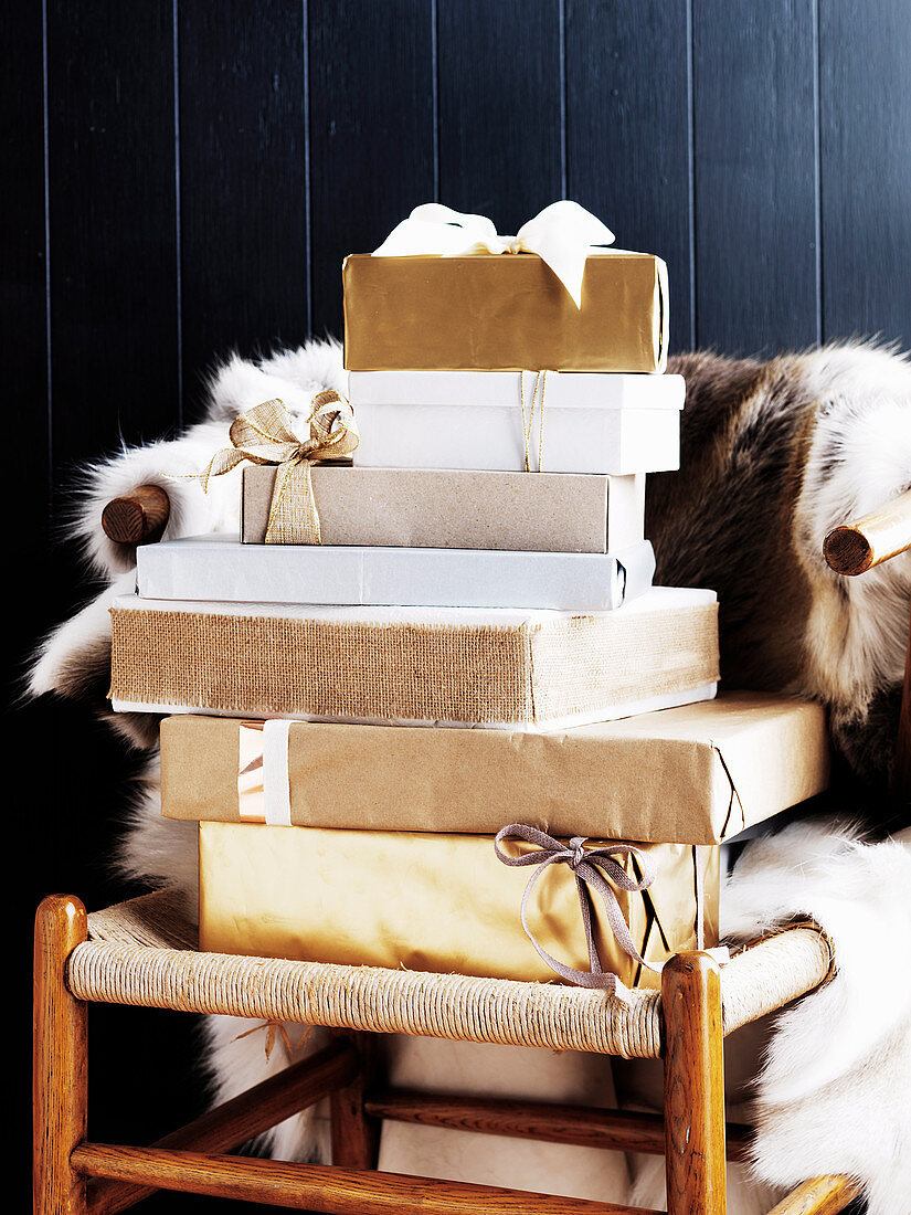 Verpackte Weihnachtsgeschenke auf Holzstuhl mit Tierfell