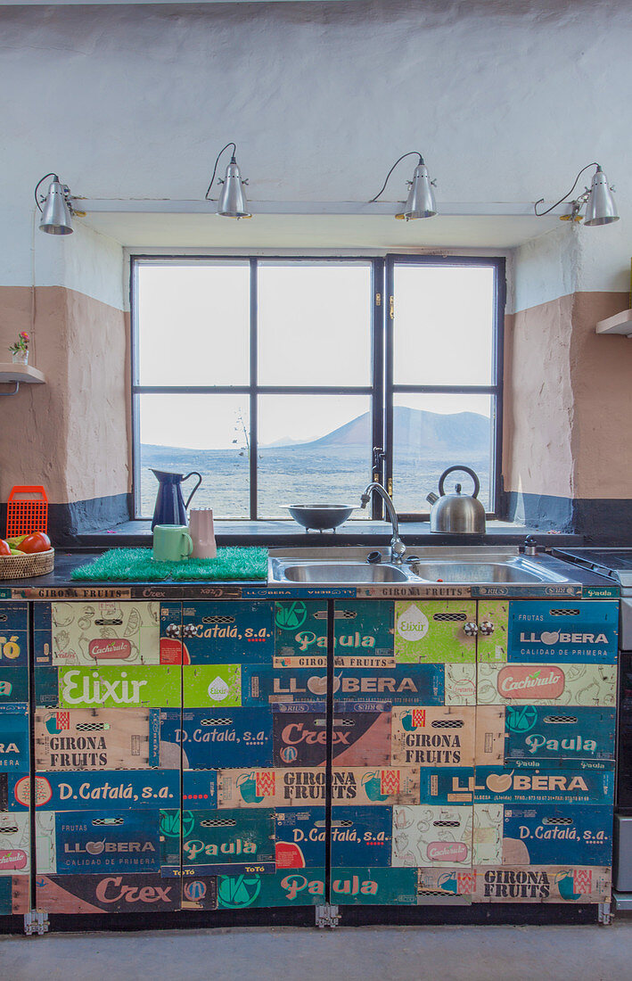 Kitchen counter covered in vintage-style wallpaper below window