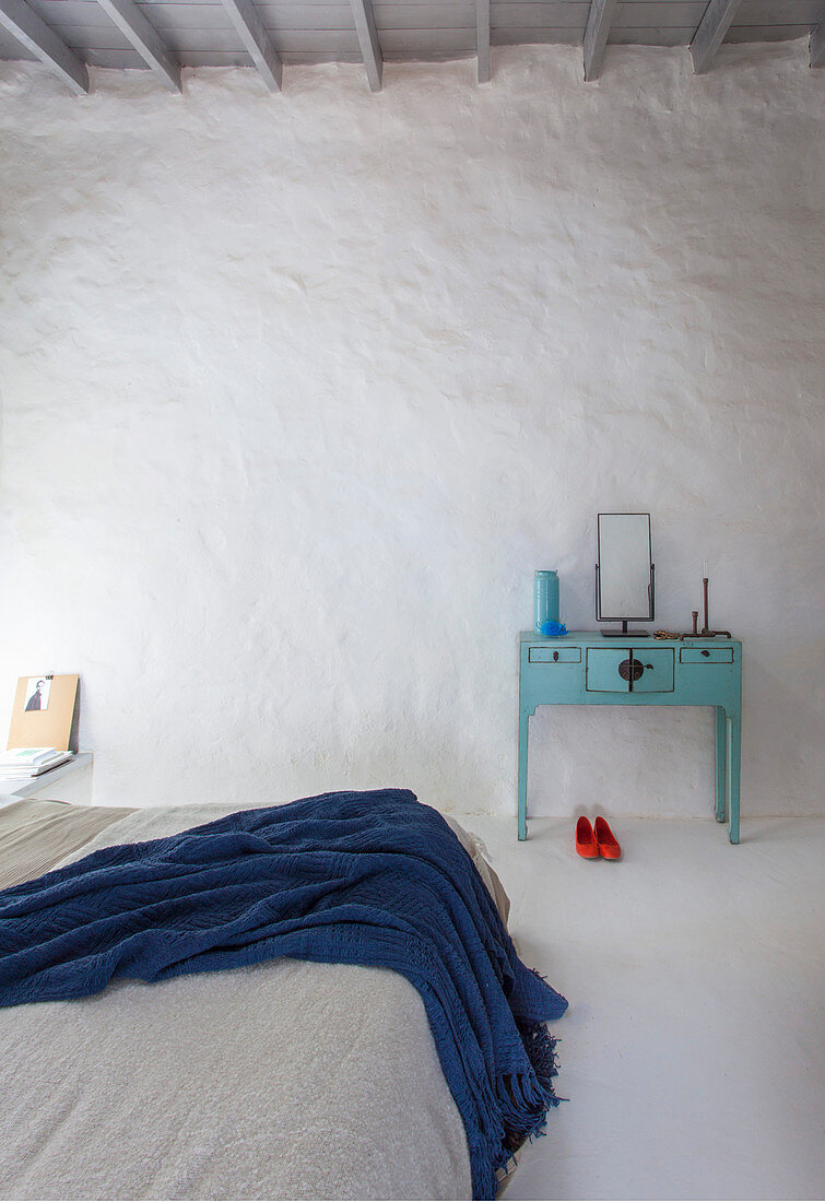 Double bed and turquoise dressing table in white-painted bedroom