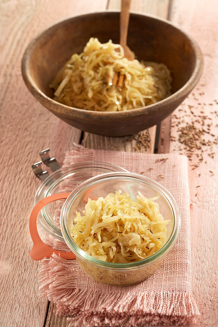 Sauerkraut made from pointed cabbage in a wooden bowl and a jar