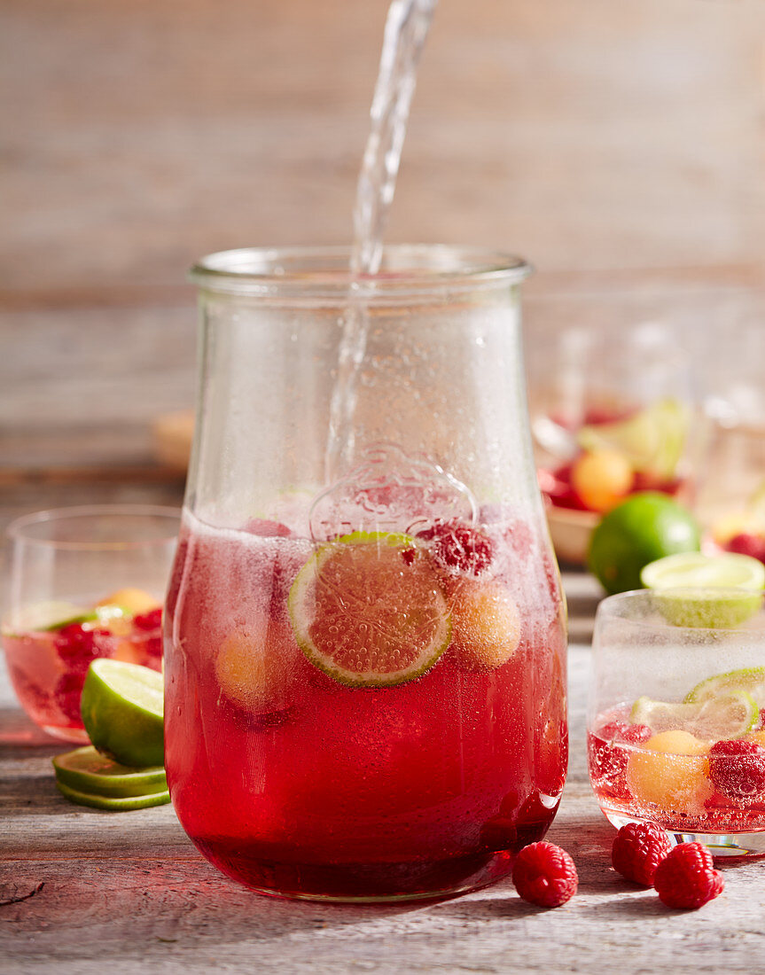 Raspberry and melon punch with champagne and limes in a jar